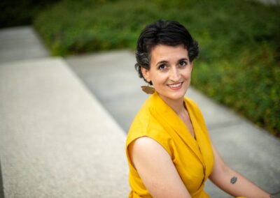 Portrait of Judit Saez in a yellow top, outdoors on a garden path