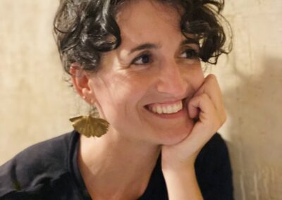 Close-up portrait of Judit Saez smiling warmly, resting her chin on her hand